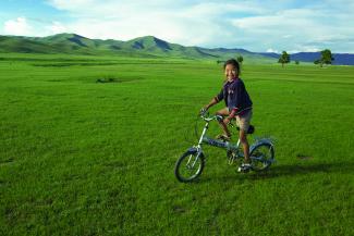 A little girl on her bike in the middle of the Mongolian steppes